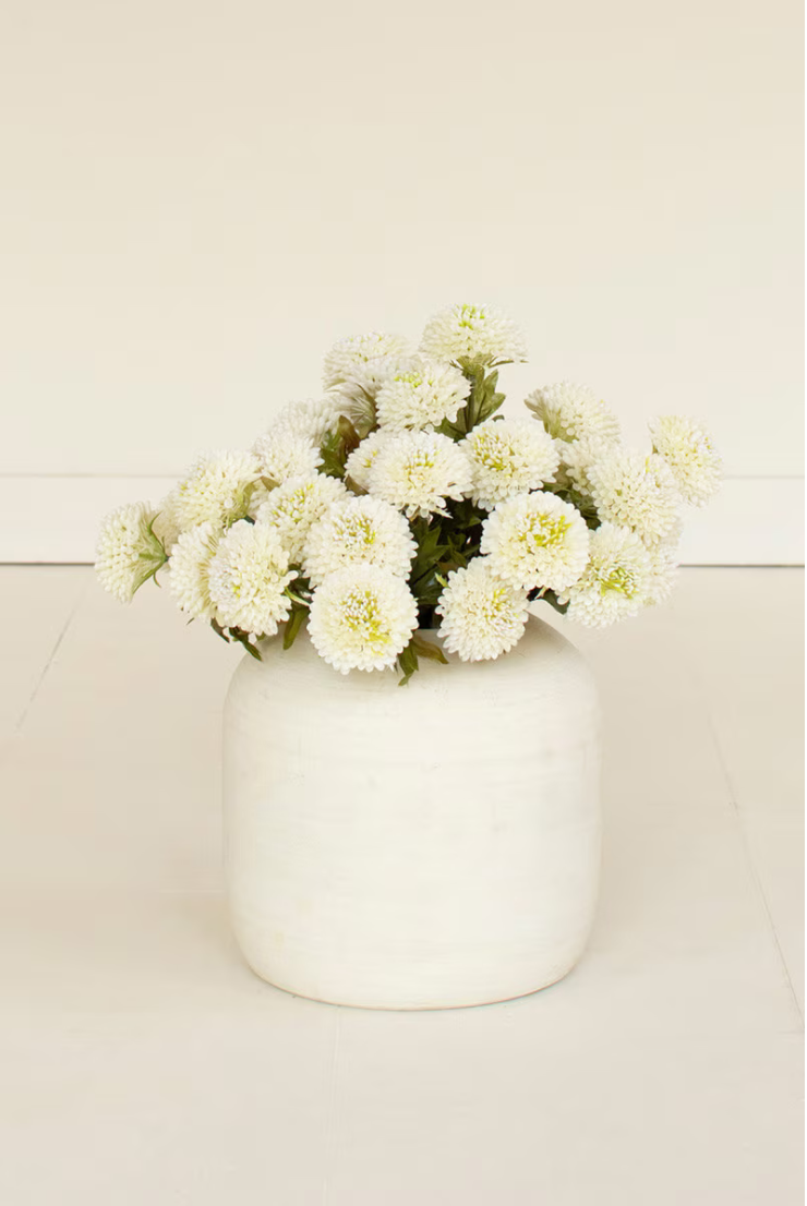 White dahlia bundle arranged in a white ceramic vase on a neutral background