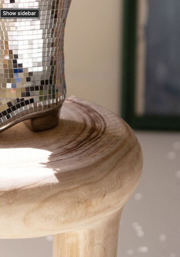 Ceramic Disco Boot Vase with flowers on wood stool, clean background