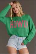 Model wearing a green Howdy lightweight sweater with pink text, front view