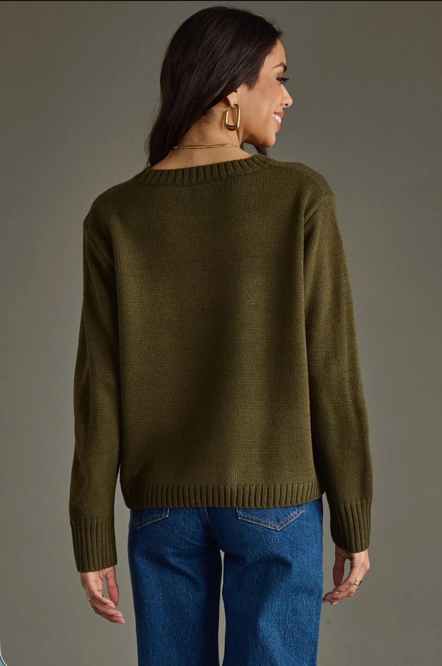 Model wearing an olive Whiskey Weather knit sweater with jeans, full body view
