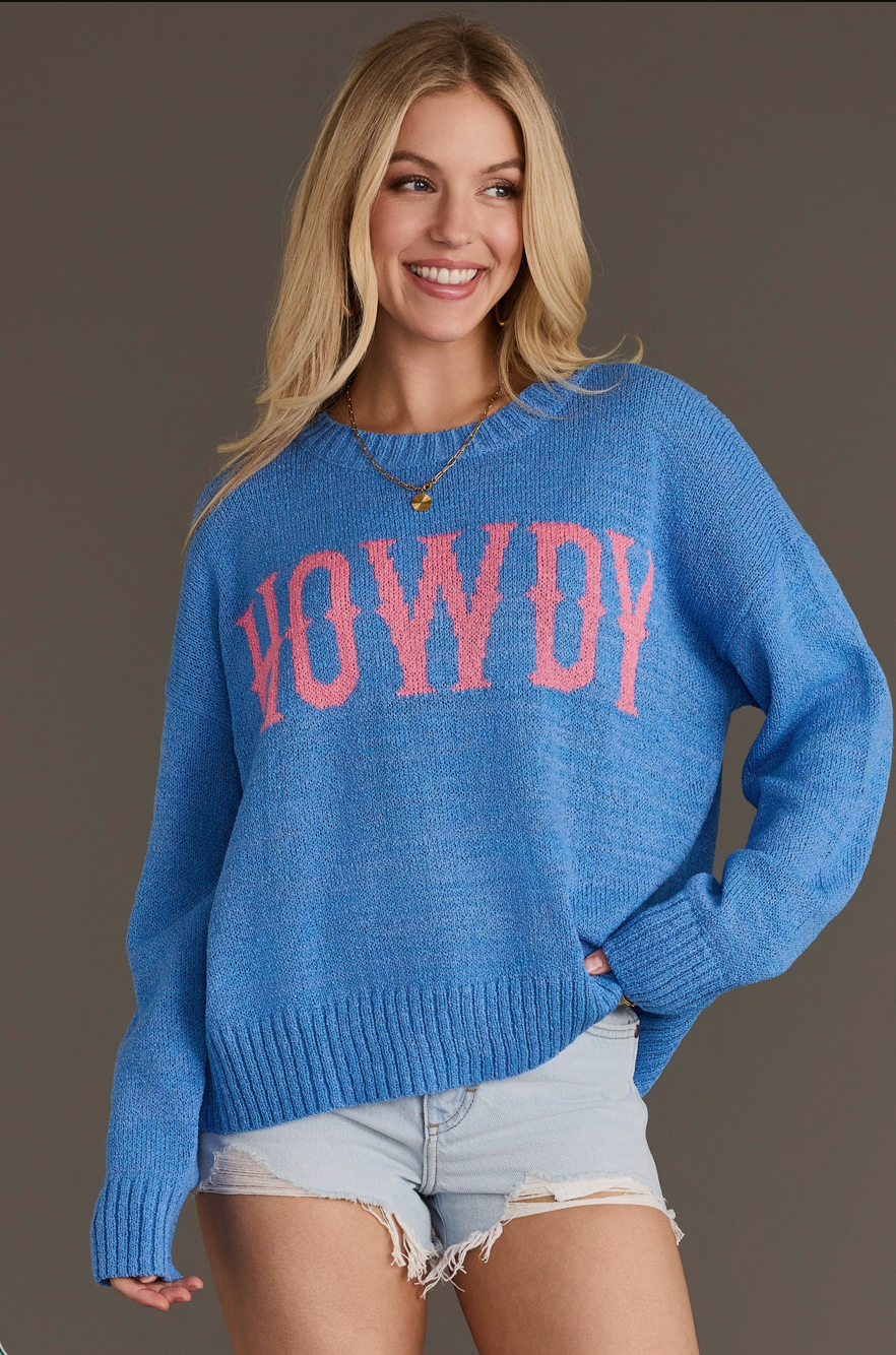 Model wearing a blue Howdy lightweight sweater with pink text, front view