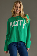 Model wearing a kelly green knit sweater with white Merry text, front view