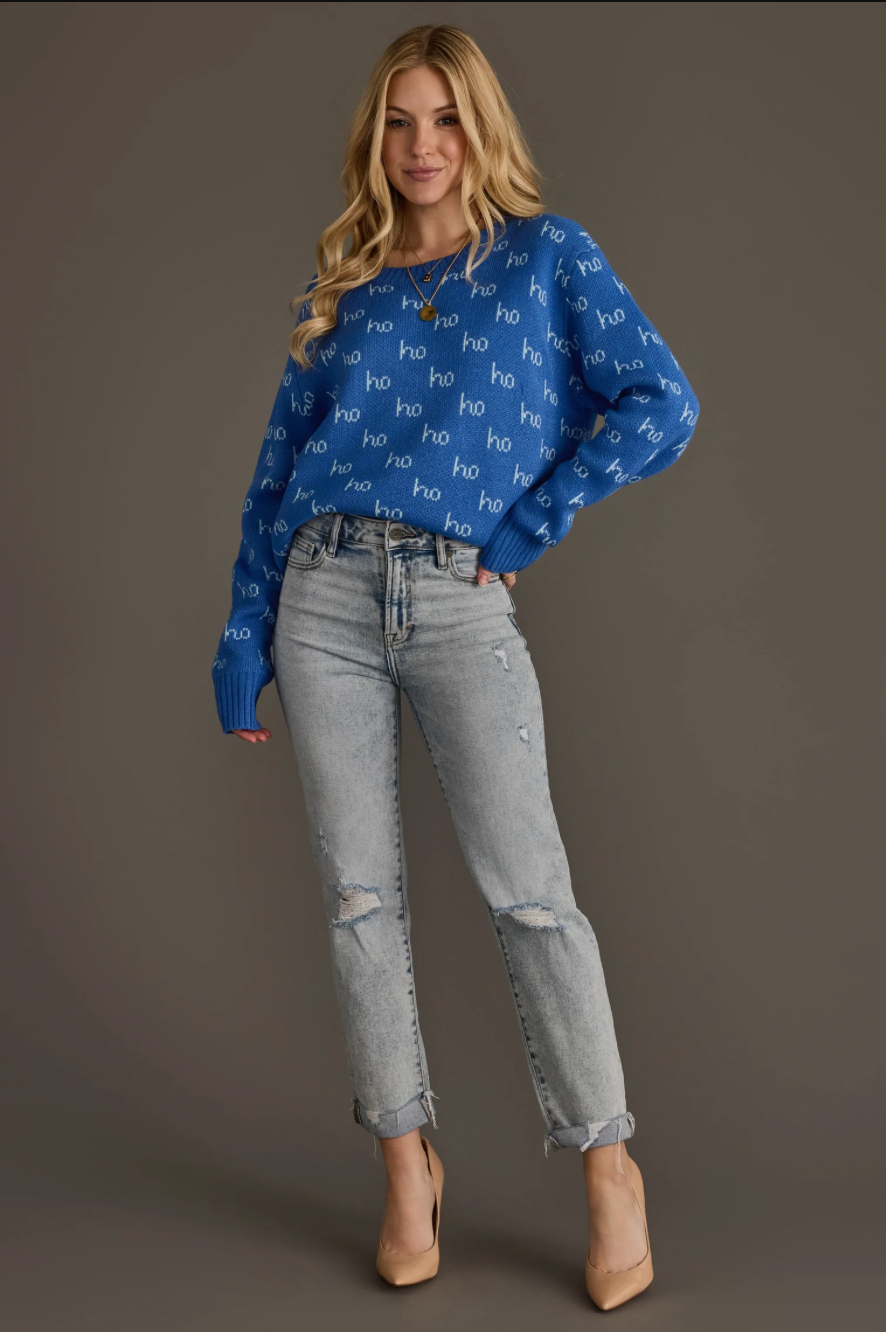 Model wearing a blue ho ho ho pattern sweater, angled full body view