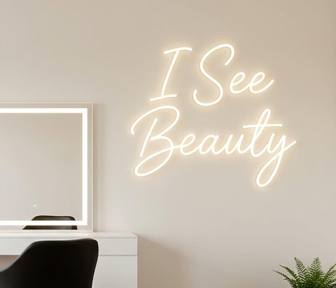 Neon sign with 'I See Beauty' on a wall in the salon with a mirror and desk.