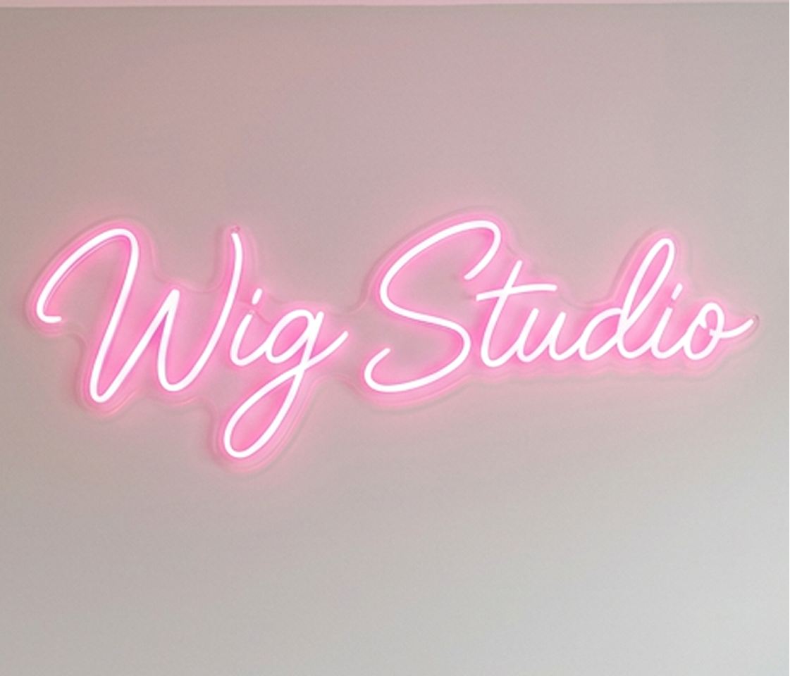 Neon sign with 'Wig Studio' text on a gradient background